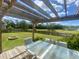 Inviting back patio with a stylish pergola and serene views of the lush backyard and tranquil pond at 303 Seneca River Dr, Summerville, SC 29485