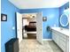 Bright bathroom with blue walls, white vanity, open doorway to bedroom and neutral tile floors at 303 Seneca River Dr, Summerville, SC 29485