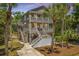 Beautiful two-story beach home with double porches, American flag, and lush tropical foliage at 607 Jungle Rd, Edisto Beach, SC 29438