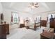 A large, comfortable bedroom with a wooden bed, soft carpet, and windows dressed with tie-back curtains at 8661 Laurel Grove Ln, North Charleston, SC 29420