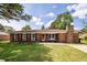 Charming brick home features a well-manicured lawn, red shutters, and inviting front porch at 104 Clover St, Summerville, SC 29483