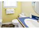 Cozy yellow bathroom with a toilet, sink with blue countertop, and white towels hung next to a window at 128 Palmetto Blvd, Edisto Beach, SC 29438
