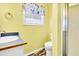Bright yellow bathroom featuring a sink, toilet, and shower area with a translucent door at 128 Palmetto Blvd, Edisto Beach, SC 29438