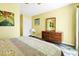 This bedroom features wood-look floors, bright, yellow walls, dresser with mirror, and closet with white doors at 128 Palmetto Blvd, Edisto Beach, SC 29438