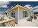 Exterior view of the home from the deck with outdoor seating under a cloudy blue sky at 128 Palmetto Blvd, Edisto Beach, SC 29438