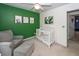 Charming Bedroom featuring a comfy chair and ottoman next to the white baby crib against a vibrant green accent wall at 1418 Whispering Oak Trl, Mount Pleasant, SC 29466
