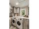 Well-lit laundry room featuring modern washer and dryer, plus gray cabinets at 15 Edgewater Aly, Isle of Palms, SC 29451