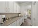 Butler's pantry with granite countertops, white cabinets, and a stylish backsplash, for added functionality at 160 Cherry Grove Dr, Summerville, SC 29483