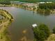 Aerial shot of a serene lake featuring a dock, surrounded by lush greenery and community buildings in a peaceful setting at 169 Callibluff Dr, Summerville, SC 29486