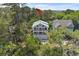 Aerial view of multi-story home featuring dual balconies and a two-car garage nestled among mature trees at 1801 Landfall Way, Seabrook Island, SC 29455