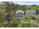 Aerial view of multi-story home featuring dual balconies and a two-car garage nestled among mature trees at 1801 Landfall Way, Seabrook Island, SC 29455