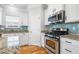 Modern kitchen with stainless steel appliances, granite countertops, white cabinets, and blue backsplash at 1817 Towne St, Johns Island, SC 29455