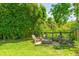 Backyard with a stone fire pit and chairs surrounded by green grass and lush greenery for relaxation at 2 Piedmont Ave # A, Charleston, SC 29403