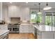 A bright kitchen boasts a large gas range, herringbone backsplash and granite counters for seamless cooking and entertainment at 2 Piedmont Ave # A, Charleston, SC 29403