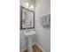 This half bathroom features a sleek pedestal sink with a modern framed mirror and wood-look flooring at 215 Shortmarsh St, Summerville, SC 29486