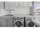 Modern laundry room with gray cabinets, white subway tile backsplash, and stainless steel washer and dryer at 259 Weeping Cypress Dr, Moncks Corner, SC 29461