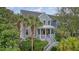 Charming coastal home with inviting porch and lush, mature landscaping and palm trees at 303 S Ladd Ct, Charleston, SC 29492
