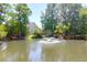 Scenic view of a pond with a fountain, framed by mature trees and the home's facade at 352 Clayton Dr, Charleston, SC 29414