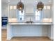 The all-white kitchen has a large island, stainless appliances, and designer pendant lighting for a modern feel at 3894 Summerton St, Mount Pleasant, SC 29466