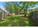 Large, grassy backyard with a wooden fence, mature trees, and well-maintained lawn at 5413 Barnsley Dr, North Charleston, SC 29420