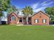 Charming brick home with a well-manicured lawn and a classic front porch, enhancing its curb appeal at 5505 Indigo Makers Trce, Charleston, SC 29418