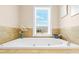 Bright bathroom featuring a large soaking tub, tiled walls, and a sunlit window offering lovely views at 656 Coleman Blvd # 405, Mount Pleasant, SC 29464
