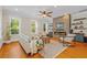 Cozy living room with a stone fireplace, ceiling fan, and three sunny windows at 656 Coleman Blvd # 405, Mount Pleasant, SC 29464