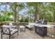 Outdoor wooden deck with modern furniture, grill, and view of surrounding trees and lawn at 7 Sconesill Ln, Charleston, SC 29414