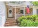 Inviting front porch featuring a brick facade, white railings, an American flag, and outdoor seating at 7 Sconesill Ln, Charleston, SC 29414