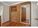 Hallway with brick wall, wood floors, and white trim around doorway to other room at 1010 Black Oak Rd, Bonneau, SC 29431