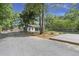 Spacious detached garage with black doors, nestled amongst mature trees, and additional parking area at 1260 Old Whitesville Rd, Moncks Corner, SC 29461