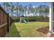 Fenced backyard featuring a well-maintained lawn, playground, and mature trees for added privacy at 127 Surfbird Rd, Summerville, SC 29486
