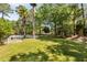 Large backyard with pool, palm trees, lush lawn, and a shaded seating area at 1505 Rivertowne Country Club Dr, Mount Pleasant, SC 29466