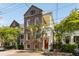 Charming brick and white two-story house with a balcony and lush trees on a sunny day at 17 Wentworth St, Charleston, SC 29401