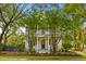 Beautiful white home with a inviting front porch framed by mature trees and lush landscaping at 2 Pagett St, Daniel Island, SC 29492