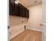 Functional laundry room with brown cabinets and hardwood floors at 208 Molasses Mill Ct, Summerville, SC 29485