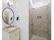 Bathroom features a walk-in shower with stone look tile, a vanity sink, and a round mirror at 221 Ashley Ave # Abc, Charleston, SC 29403