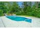 A beautiful in-ground pool featuring clean white trim and ladder entry, surrounded by lush greenery and ample seating at 23 Forde Row, Charleston, SC 29412
