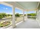 Expansive balcony with elegant columns, white railings, and scenic views of lush landscaping and a fountain at 2636 Anchor Watch Dr, Wadmalaw Island, SC 29487