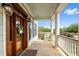 Inviting porch with white columns, railing, a wooden door and a view of a lush green lawn at 2636 Anchor Watch Dr, Wadmalaw Island, SC 29487