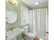 Well-lit bathroom features a pedestal sink, toilet, shower with curtain, and a round mirror at 3104 Upda Creek, Seabrook Island, SC 29455