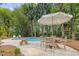 Inviting pool area with an umbrella covered dining set surrounded by mature trees and a playhouse at 312 E Shepard Ln, Summerville, SC 29483