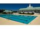 A community pool with clear water and a nearby clubhouse under a bright blue sky, inviting residents for relaxation and recreation at 320 Foxglove Ave, Summerville, SC 29483