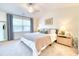 This bright bedroom with ceiling fan features a plush bed, bedside table, and large window at 3208 Pecan Orchard Way, Charleston, SC 29414