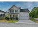 Traditional two-story home featuring a neat lawn, an attached garage, and a covered front porch with an American flag at 3208 Pecan Orchard Way, Charleston, SC 29414