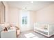 Bright Bedroom with a white crib, neutral chair, and a large window creating a cozy atmosphere at 325 Tiliwa St, Summerville, SC 29486