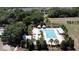 Aerial view of a pool with sunshades surrounded by landscaping and a field with trees and homes at 3997 Aspera Dr, Summerville, SC 29483