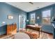 A sunlit home office with blue walls features a wooden desk and a stylish area rug and connects to a bathroom at 49 Ashley Ave, Charleston, SC 29401