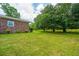 View of the spacious backyard, showcasing a brick home exterior and mature trees creating a private setting at 5823 Lakeview Dr, Hanahan, SC 29410
