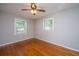 A luminous bedroom featuring hardwood floors, two bright windows, and a ceiling fan with lighting at 5823 Lakeview Dr, Hanahan, SC 29410